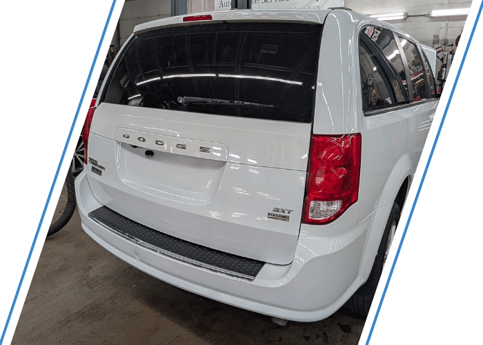 White Dodge Grand Caravan inside an automotive repair shop for service and maintenance.