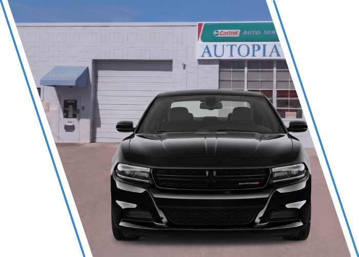 Front view of a black Dodge sedan parked outside an auto repair shop.