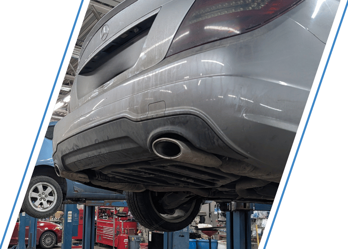 Rear underside of a Mercedes-Benz on a lift showing the exhaust system during emissions inspection.