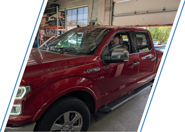 Red Ford F-150 pickup arriving at an automotive repair facility for service.