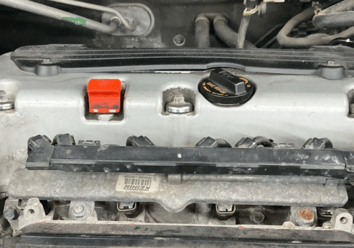 Close-up of a vehicle engine with the valve cover removed, highlighting the fuel injector area