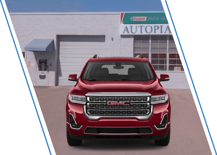 Front view of a red GMC SUV parked outside an auto repair shop.