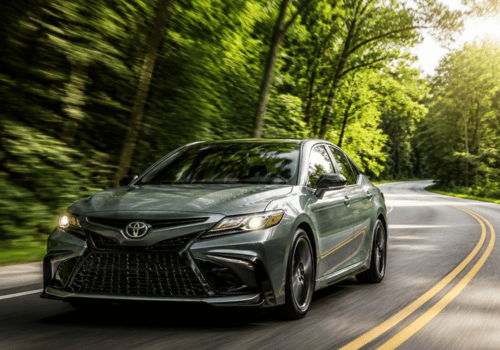 Toyota Camry sedan driving along a scenic, tree-lined road