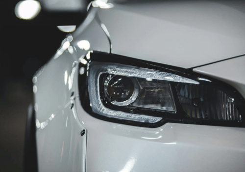 Close-up of a modern vehicle headlight assembly on a white car