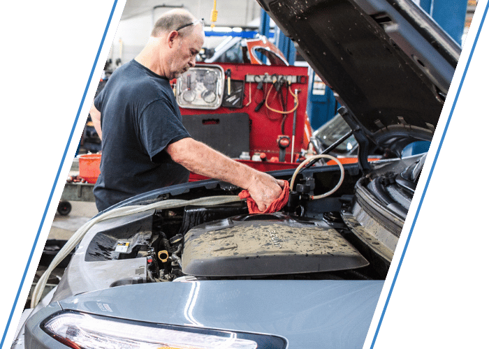 Technician servicing the engine compartment of a hybrid or electric vehicle.