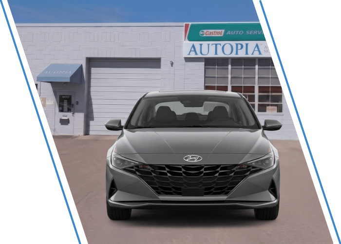 Front view of a gray Hyundai sedan parked outside an auto repair shop.