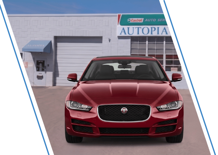 Front view of a red Jaguar sedan parked outside an auto repair shop.