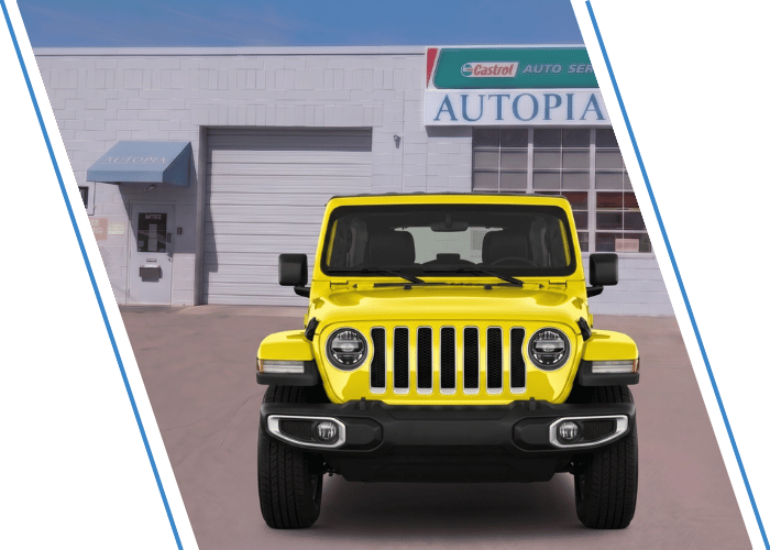 Front view of a yellow Jeep Wrangler parked outside an auto repair shop.