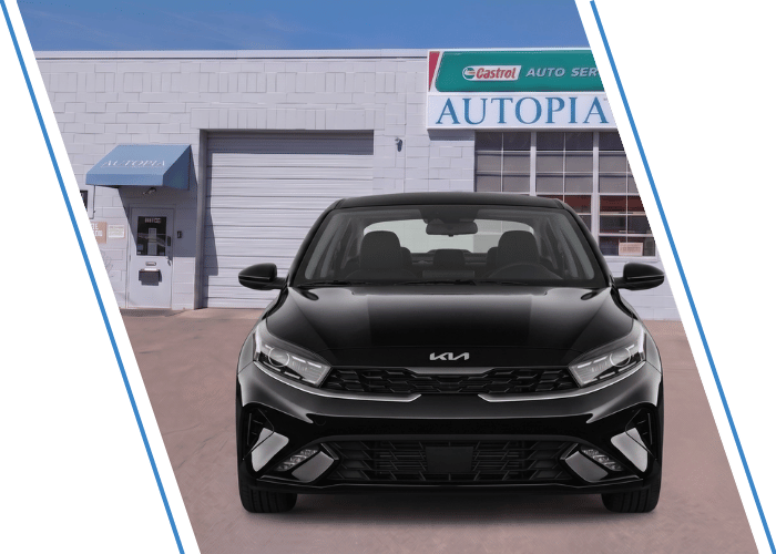 Front view of a black Kia sedan parked outside an auto repair shop.