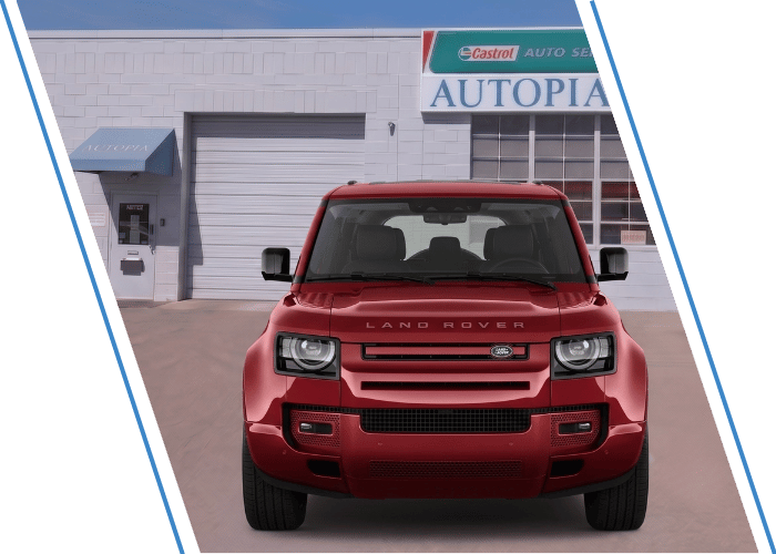 Front view of a red Land Rover SUV parked outside an auto repair shop.