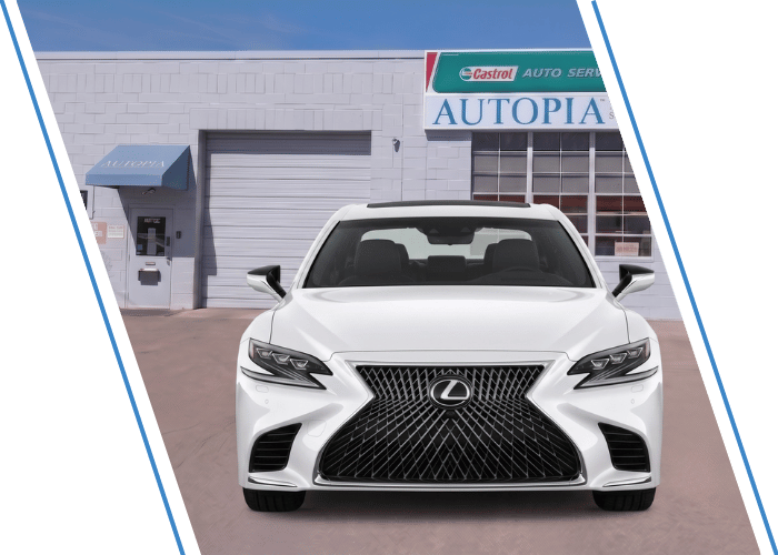 Front view of a white Lexus sedan parked outside an auto repair shop.