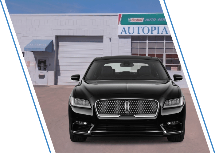 Front view of a black Lincoln sedan parked outside an auto repair shop.