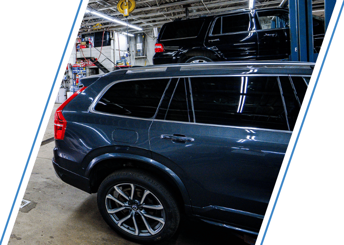 SUV parked inside a professional auto repair shop with additional vehicles on service lifts.