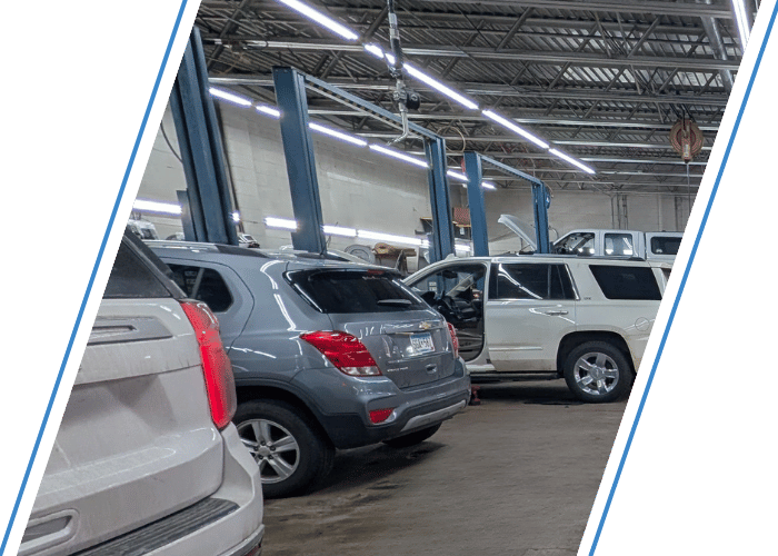 Multiple SUVs lined up inside a busy automotive repair facility awaiting maintenance and repairs.