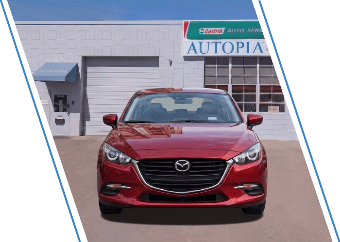 Front view of a red Mazda sedan parked outside an auto repair shop.
