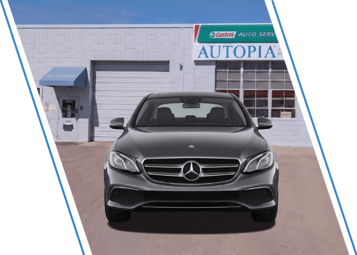 ront view of a gray Mercedes-Benz sedan parked outside an auto repair shop.