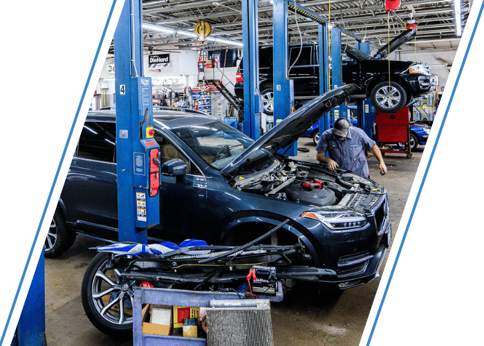 Technician performing engine diagnostics on a SUV inside a professional repair shop.