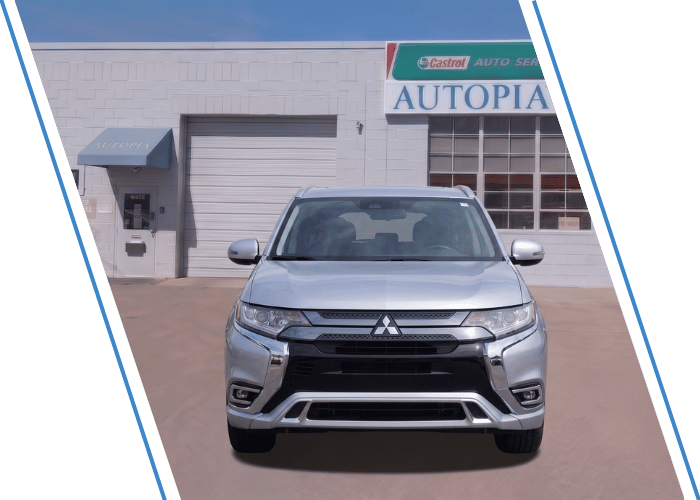 Front view of a silver Mitsubishi SUV parked outside an auto repair shop.