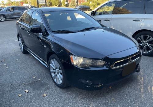 Black Mitsubishi Lancer sedan parked outdoors in a parking lot
