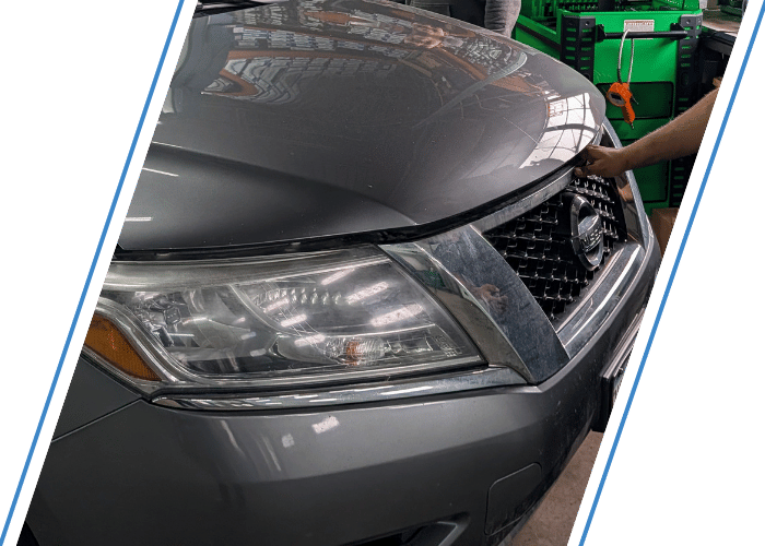 Technician inspecting the front of a Nissan SUV during automotive diagnostics and repair.