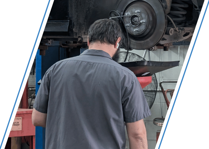 Technician draining engine oil from a vehicle on a lift during routine maintenance.