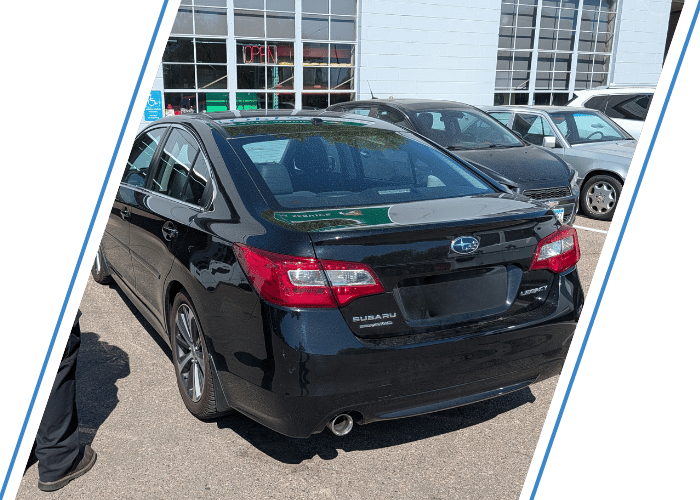 Black Subaru Legacy parked outside an automotive repair shop before scheduled service.