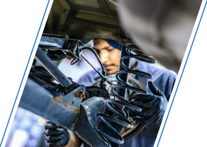 Technician installing a suspension coil spring during steering and suspension repair.