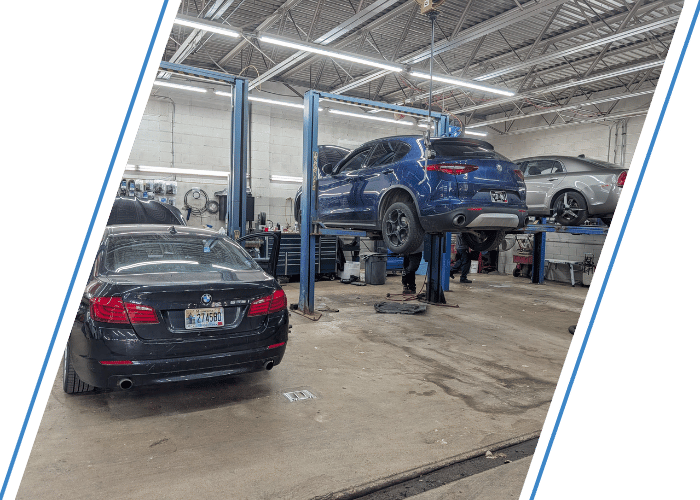 Luxury vehicles on hydraulic lifts inside a modern auto repair facility during maintenance.