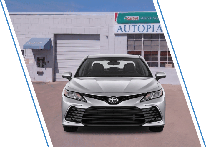 Front view of a silver Toyota sedan parked outside an auto repair shop.