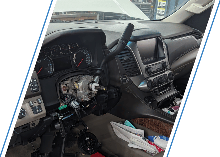Vehicle interior with steering column disassembled during transmission-related diagnostics and repair.