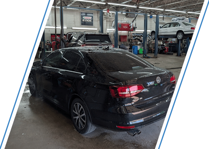 Black Volkswagen sedan inside a professional repair shop after automotive service and inspection.