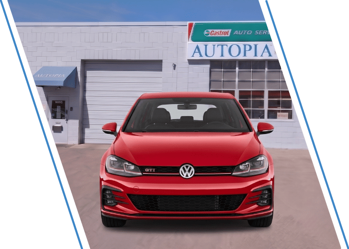 Front view of a red Volkswagen hatchback parked outside an auto repair shop.