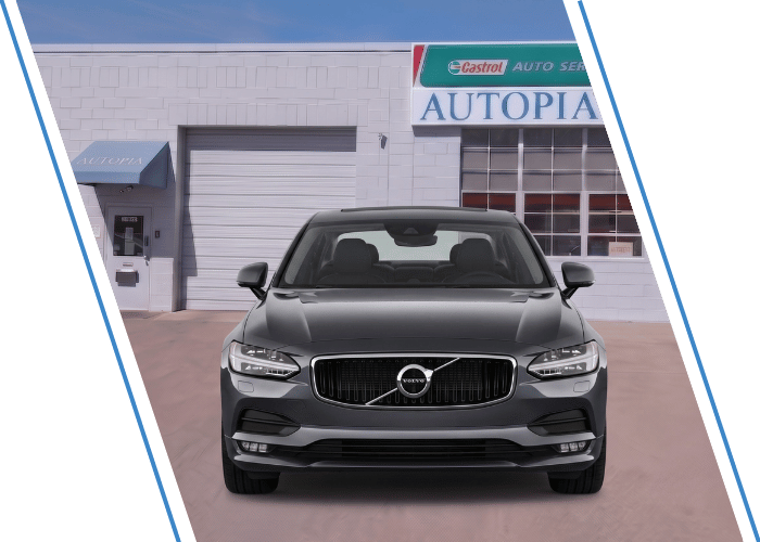 Front view of a gray Volvo sedan parked outside an auto repair shop.