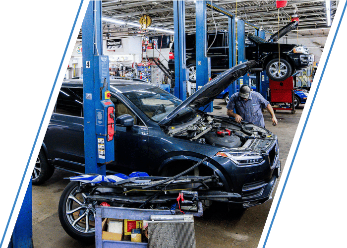 Technician performing engine diagnostics on a SUV inside a professional repair shop.