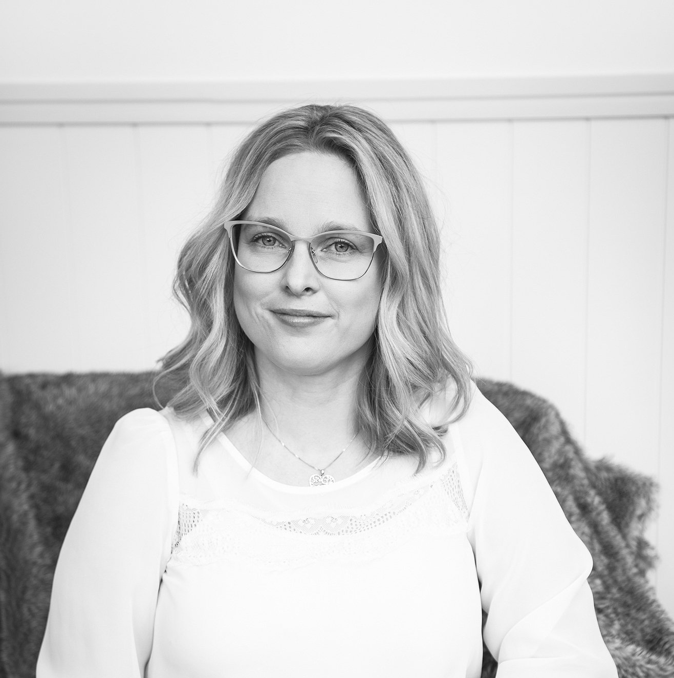 Lana seated on a couch, facing the camera with a slight smile.