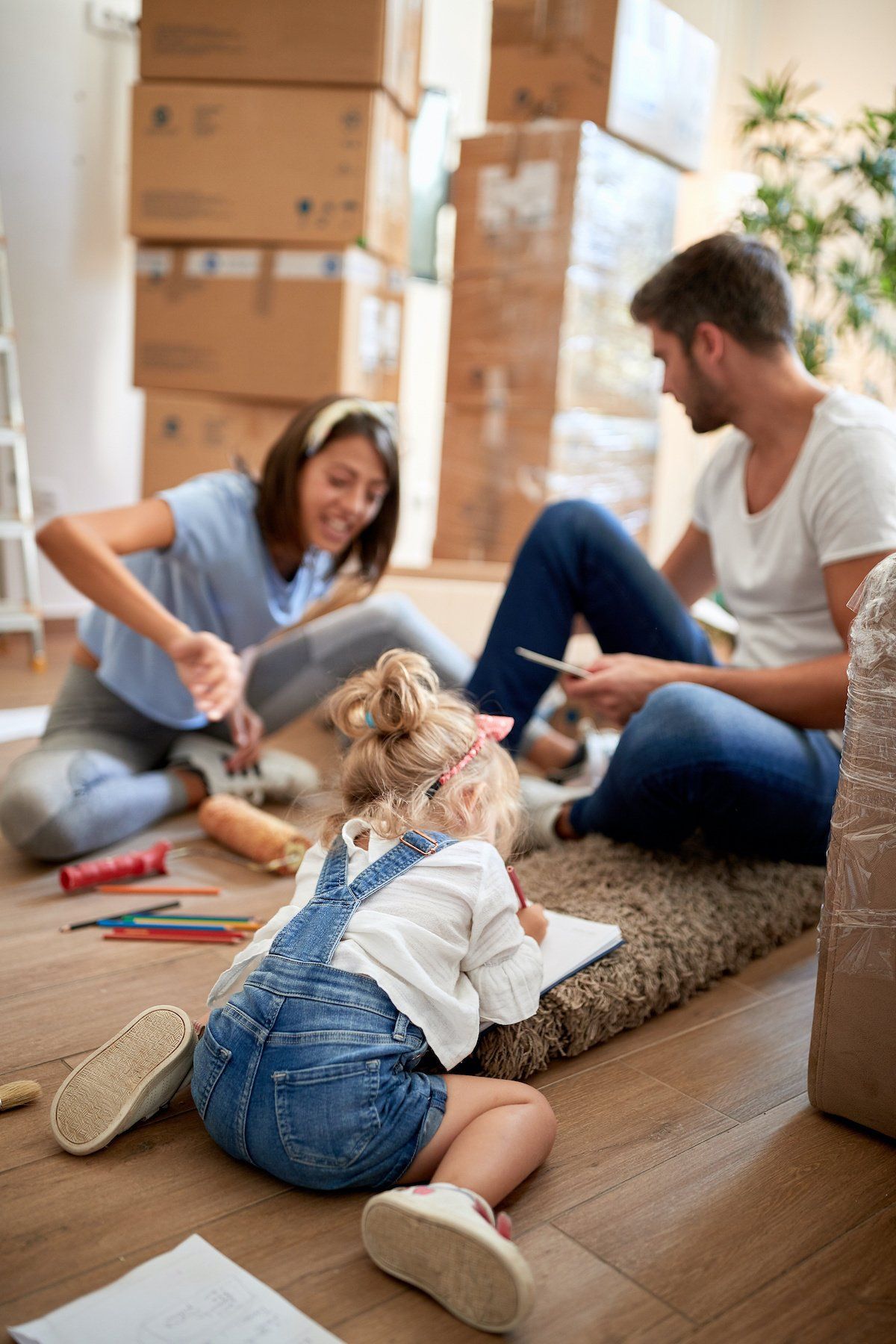 Family unpacking boxes and playing with a small dog on the floor in a living room