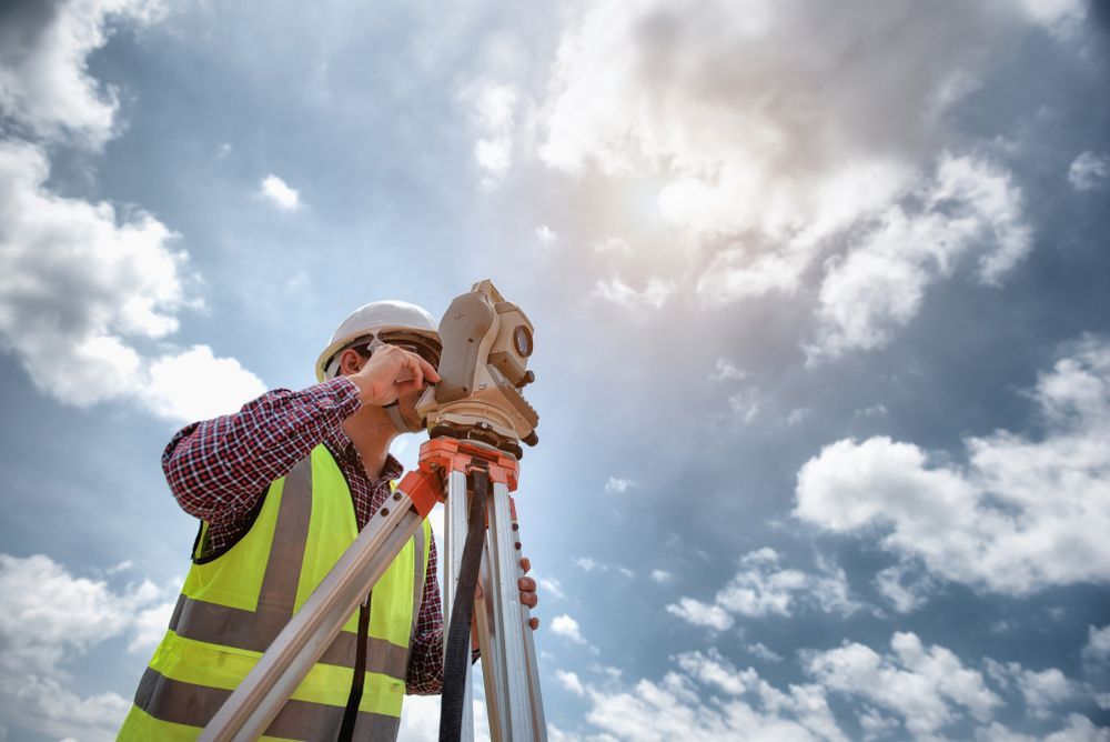 A Construction Worker Is Using a Theodolite on A Tripod — Hager Surveying In Kyogle, NSW