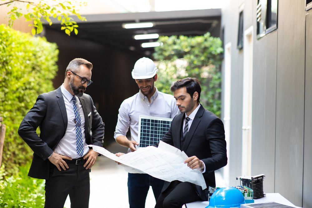 A Group of Men in Suits and Ties Are Looking at A Blueprint — Hager Surveying In Tweed Heads, NSW