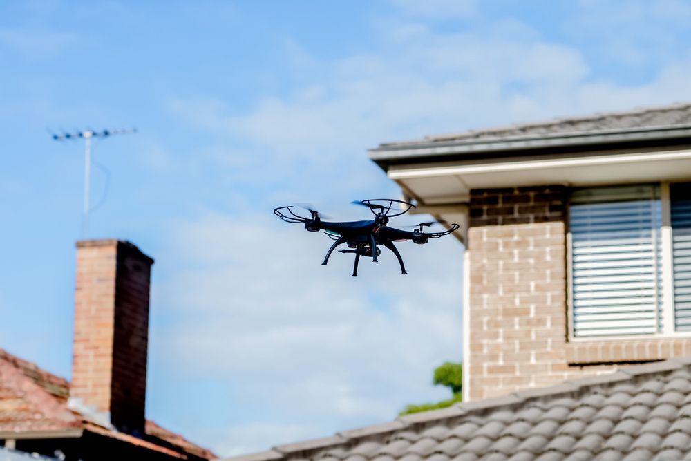 A Drone Is Flying Over a Brick House — Hager Surveying In Coolangatta, QLD