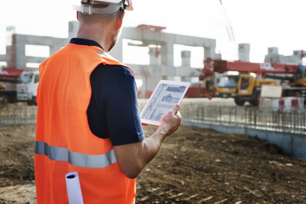 A Construction Worker Is Looking at A Tablet at A Construction Site — Hager Surveying In Banora Point, NSW