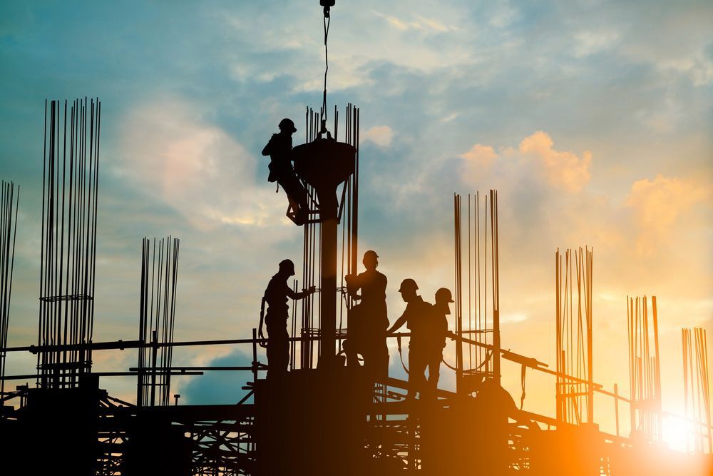 A Group of Construction Workers Are Working on A Building Under Construction at Sunset — Hager Surveying In Kingscliff, NSW