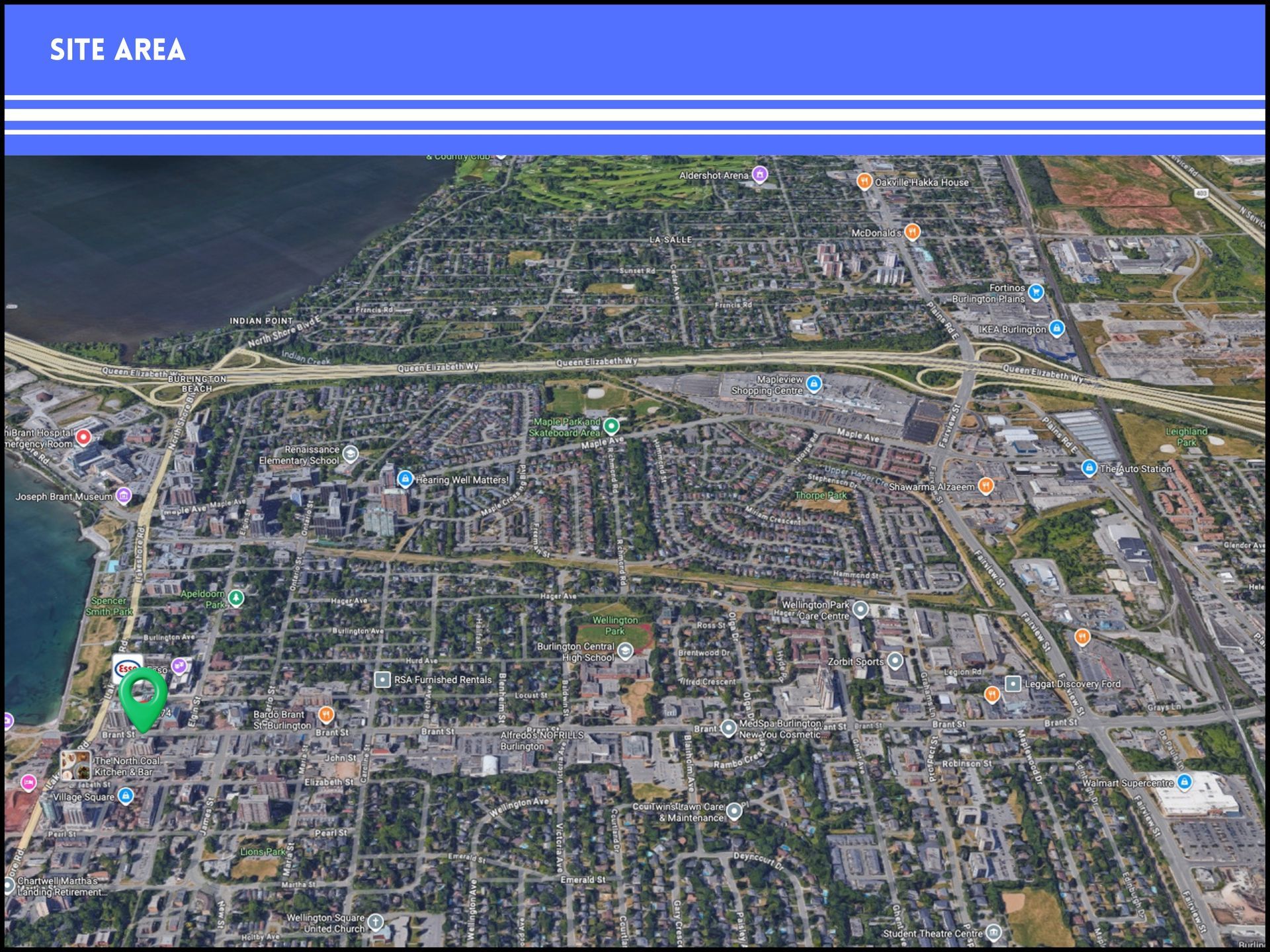 An aerial view of a city neighborhood, with a green pin icon marking a specific site area near a waterfront.