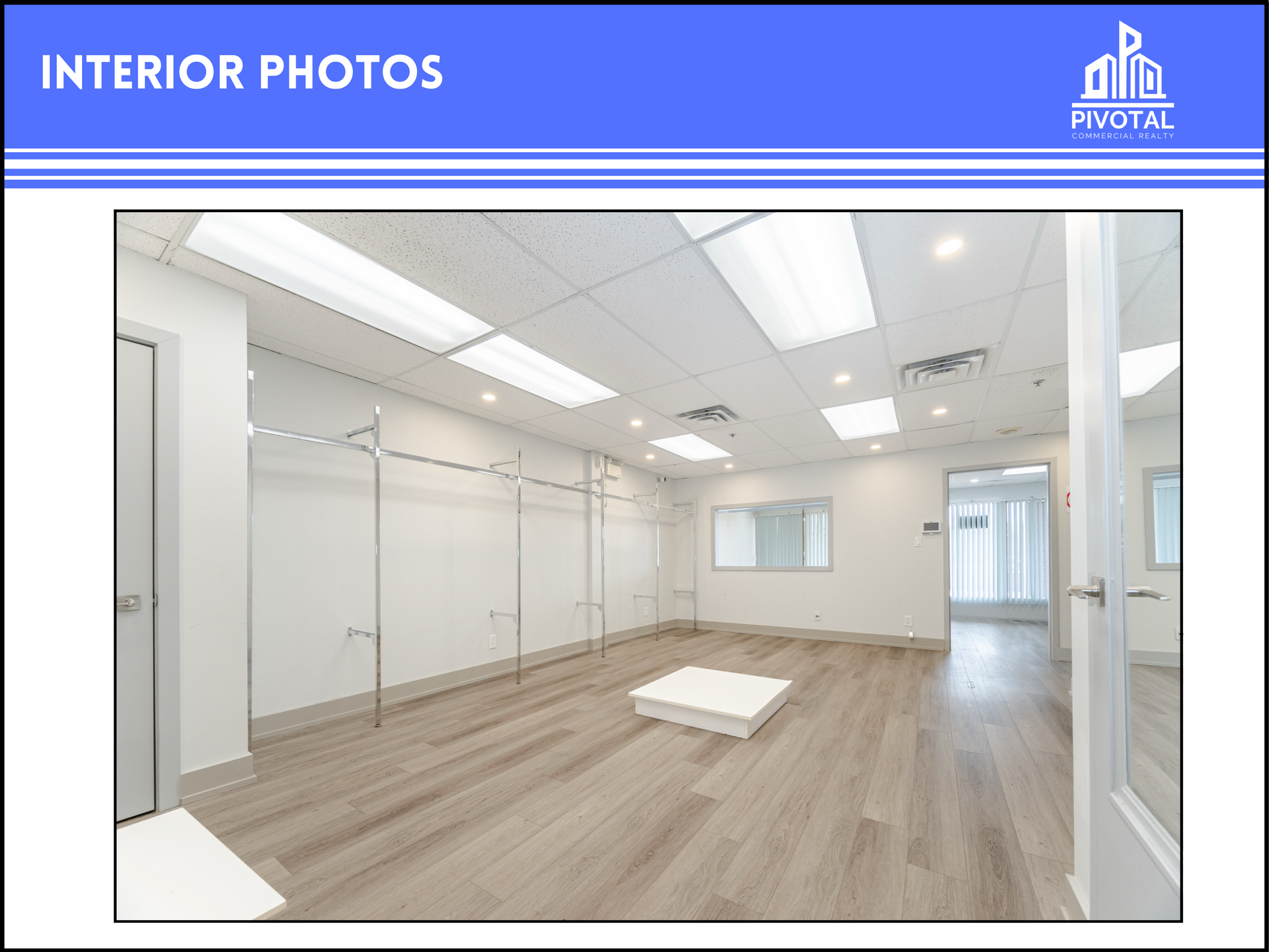 A bright, empty retail space with light wood floors, white walls, metal clothing racks, and recessed ceiling lights.