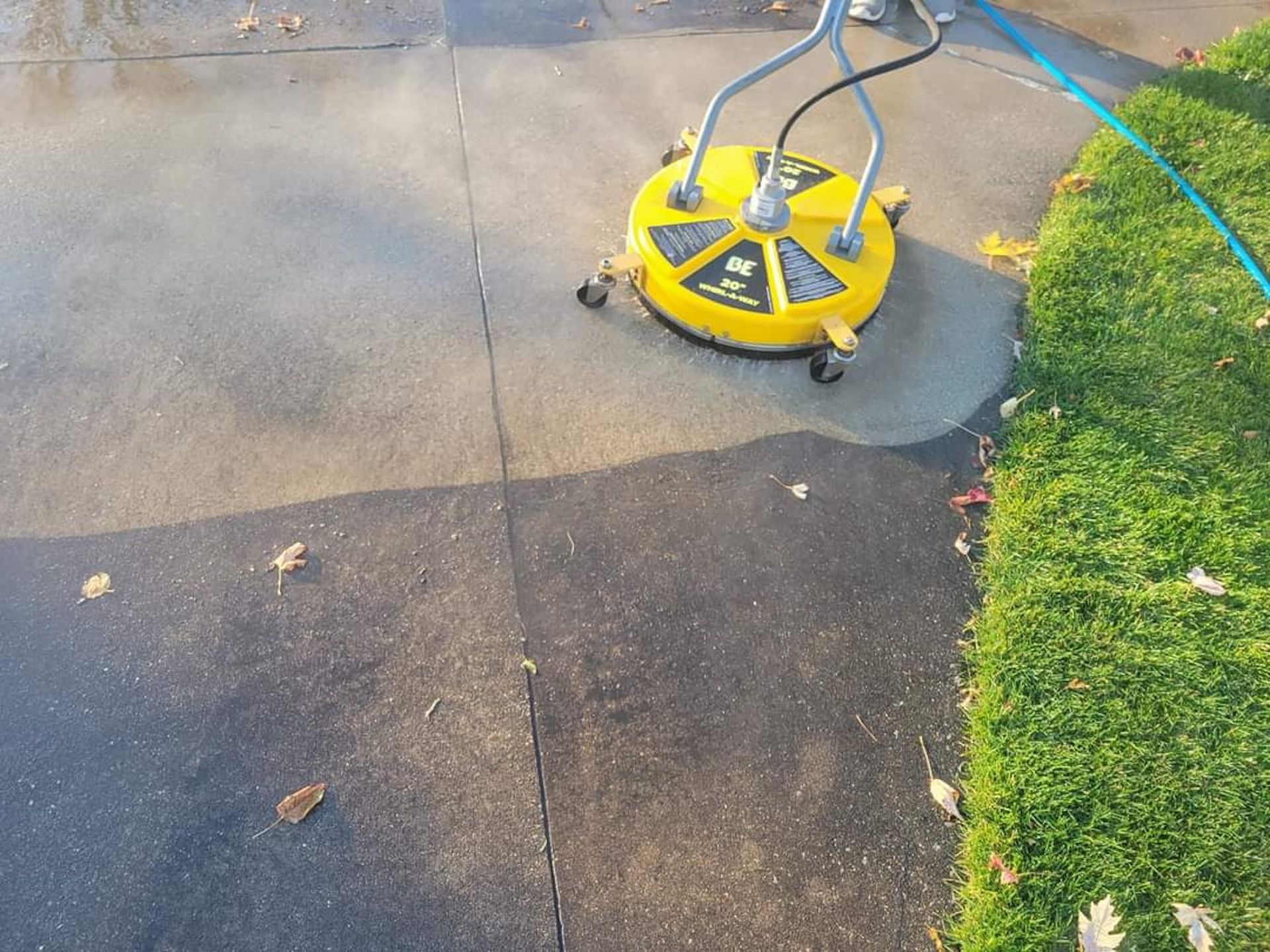 Yellow surface cleaner on a driveway, cleaning the concrete.