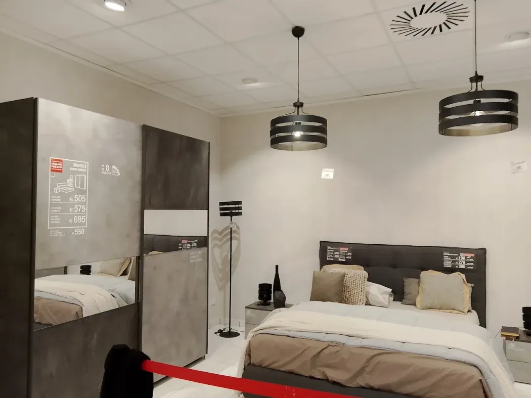 Camera da letto moderna con due letti, armadio grigio e lampade a sospensione nere sotto un soffitto bianco.