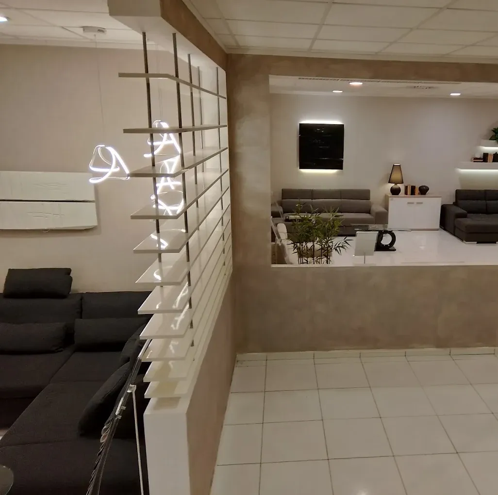 Hall moderna con divano nero, divisorio bianco, banco reception e pavimento piastrellato.