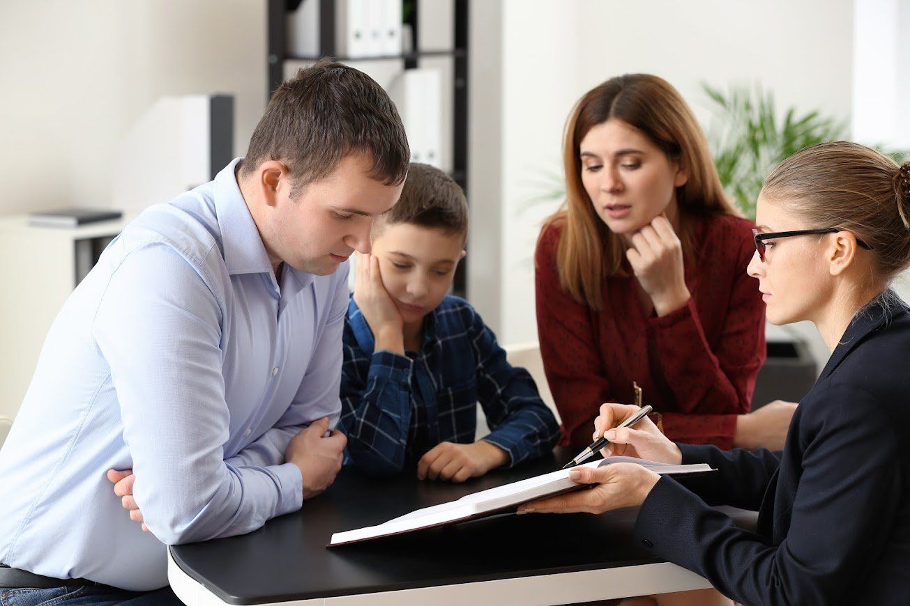 Family meeting with a counselor; people looking at a document.
