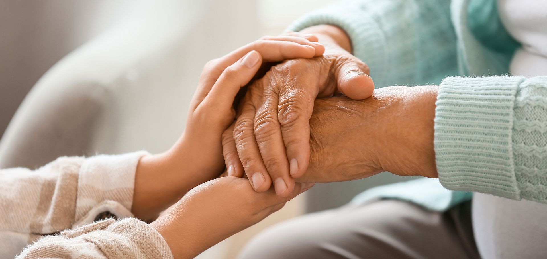 Senior woman with daughter holding hands at home. Senior woman with daughter holding hands at home.