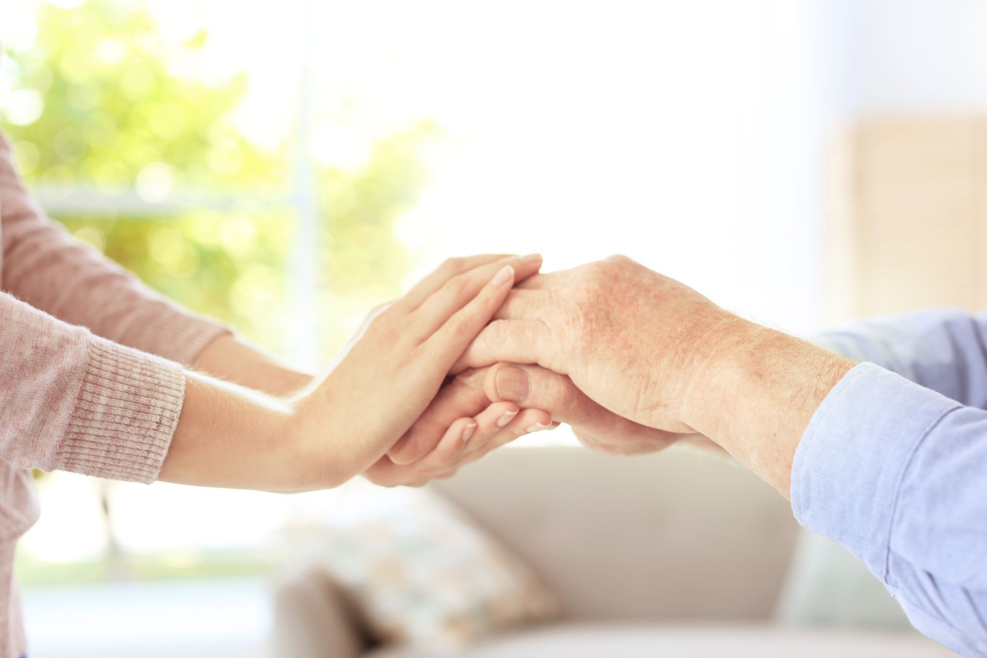 Caregiver holding senior's hand, home health care agency support