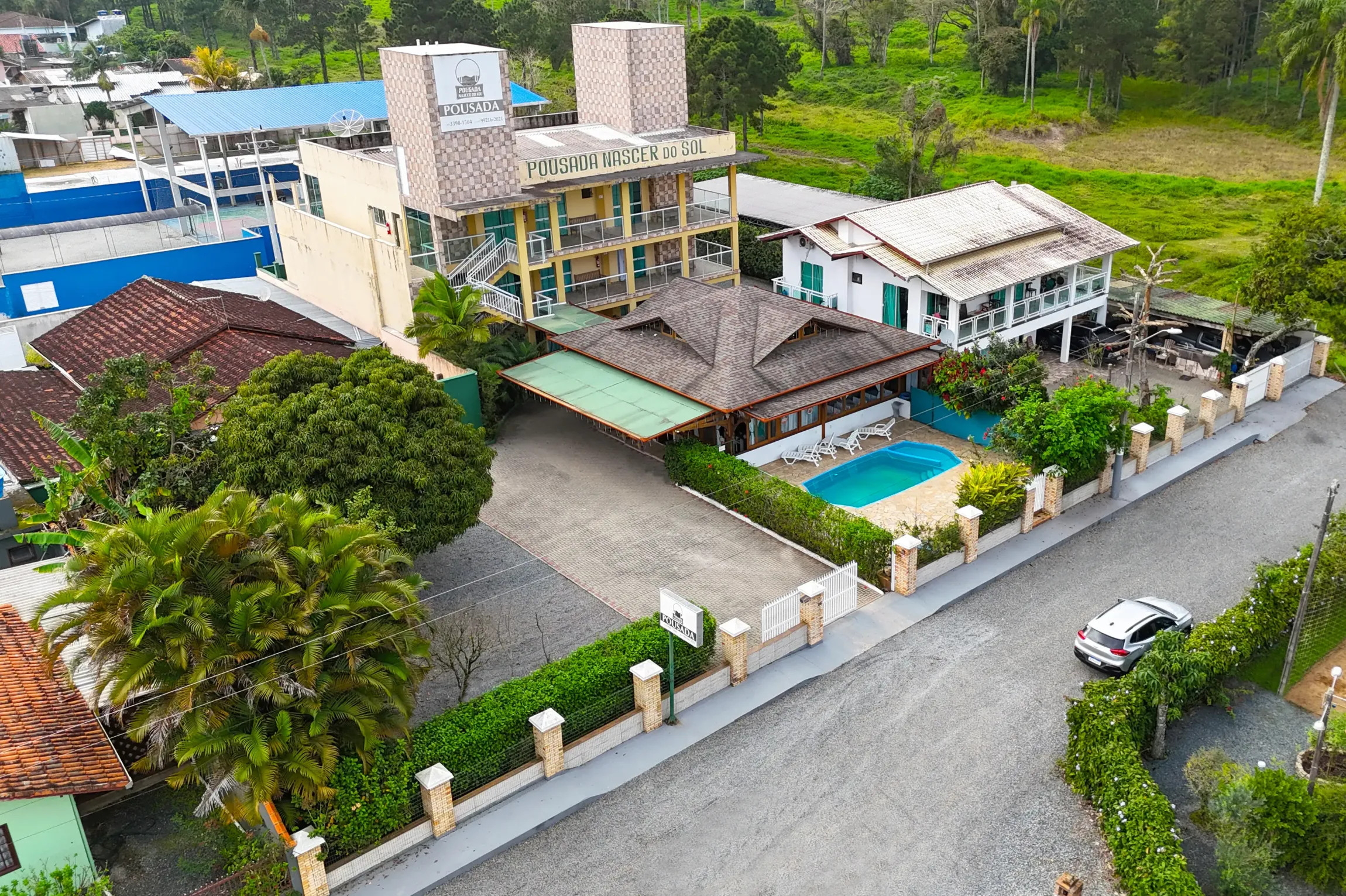 Piscina com uma queda d'água com casa de madeira ao fundo-Pousada-Nascer do Sol